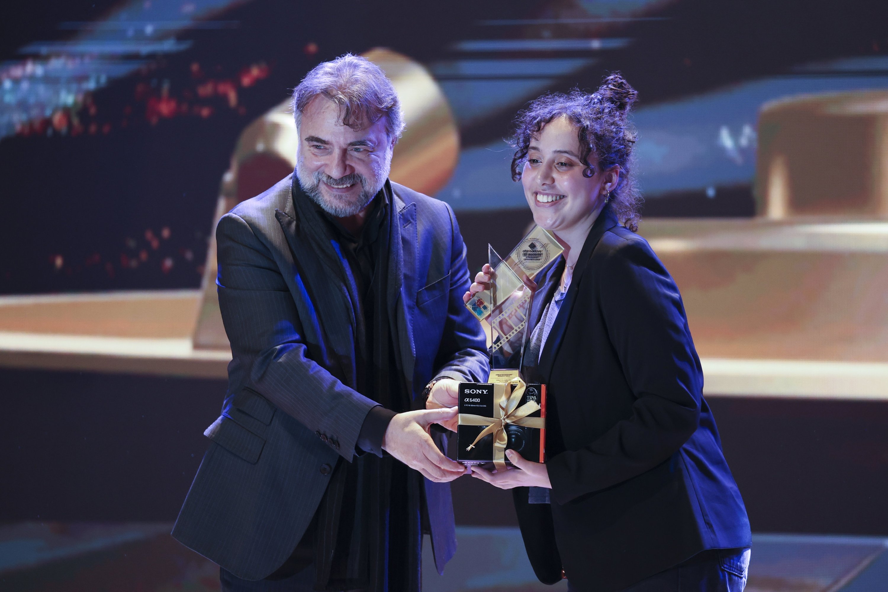 Renowned Turkish actor Oktay Kaynarca presents the award to director Cerine Raouraoua for her animated film