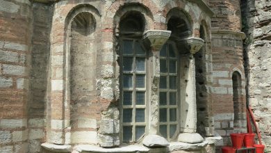 Brick and stone apse of an old Byzantine-style building in Istanbul, with arched windows and red fire buckets nearby