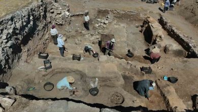 Aerial view of archaeologists working in an excavation trench with stone walls, buckets and baskets at an ancient dig site
