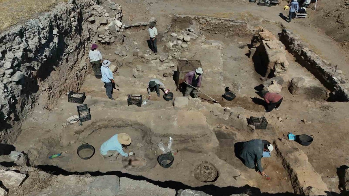 Aerial view of archaeologists working in an excavation trench with stone walls, buckets and baskets at an ancient dig site