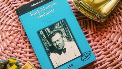 Paperback copy of the novel Kürk Mantolu Madonna with a black-and-white author portrait, lying on a pink wicker mat beside a toy car