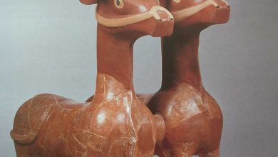 Pair of ancient Hittite-style terracotta bull statues with long curved horns on a white display plinth
