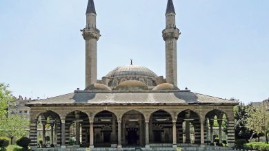 Ottoman-style mosque with two slender minarets, a central dome, an arcaded portico of striped stonework and a fountain pool in front.