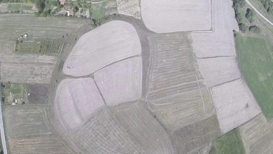 Aerial view of a rounded mound surrounded by plowed farm fields, roads and houses, apparently the Tavşanlı Höyük archaeological site