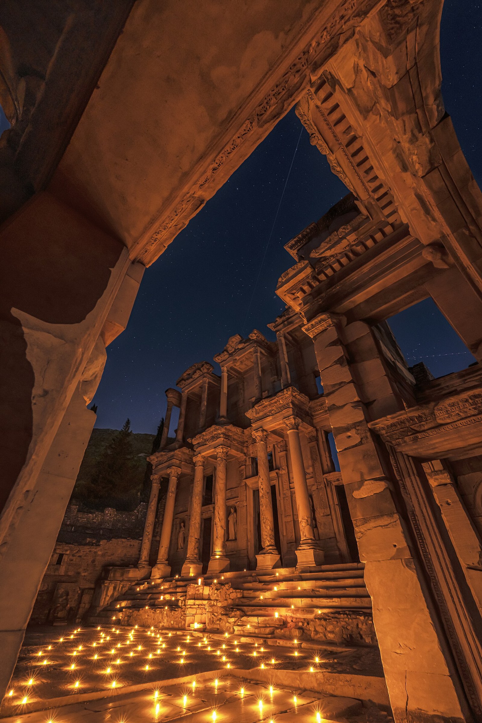Illuminated ancient ruins of Ephesus at night with candles on the ground