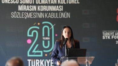 Woman in a navy blazer speaks at a podium before a backdrop marking 20 years of UNESCO's intangible heritage convention in Türkiye