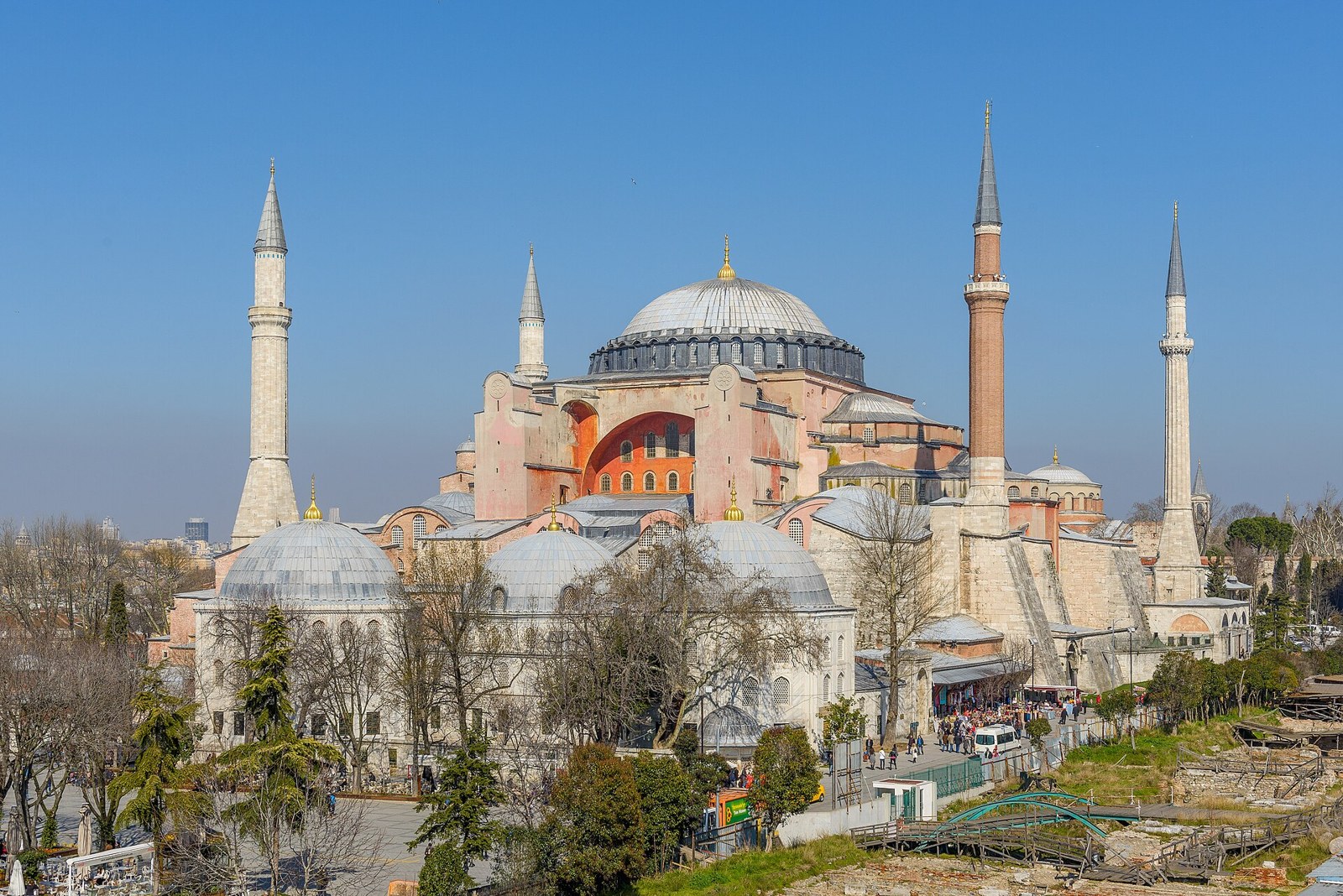 Hagia Sophia in Istanbul under a clear blue sky, with its large central dome, four minarets and bare trees in the foreground